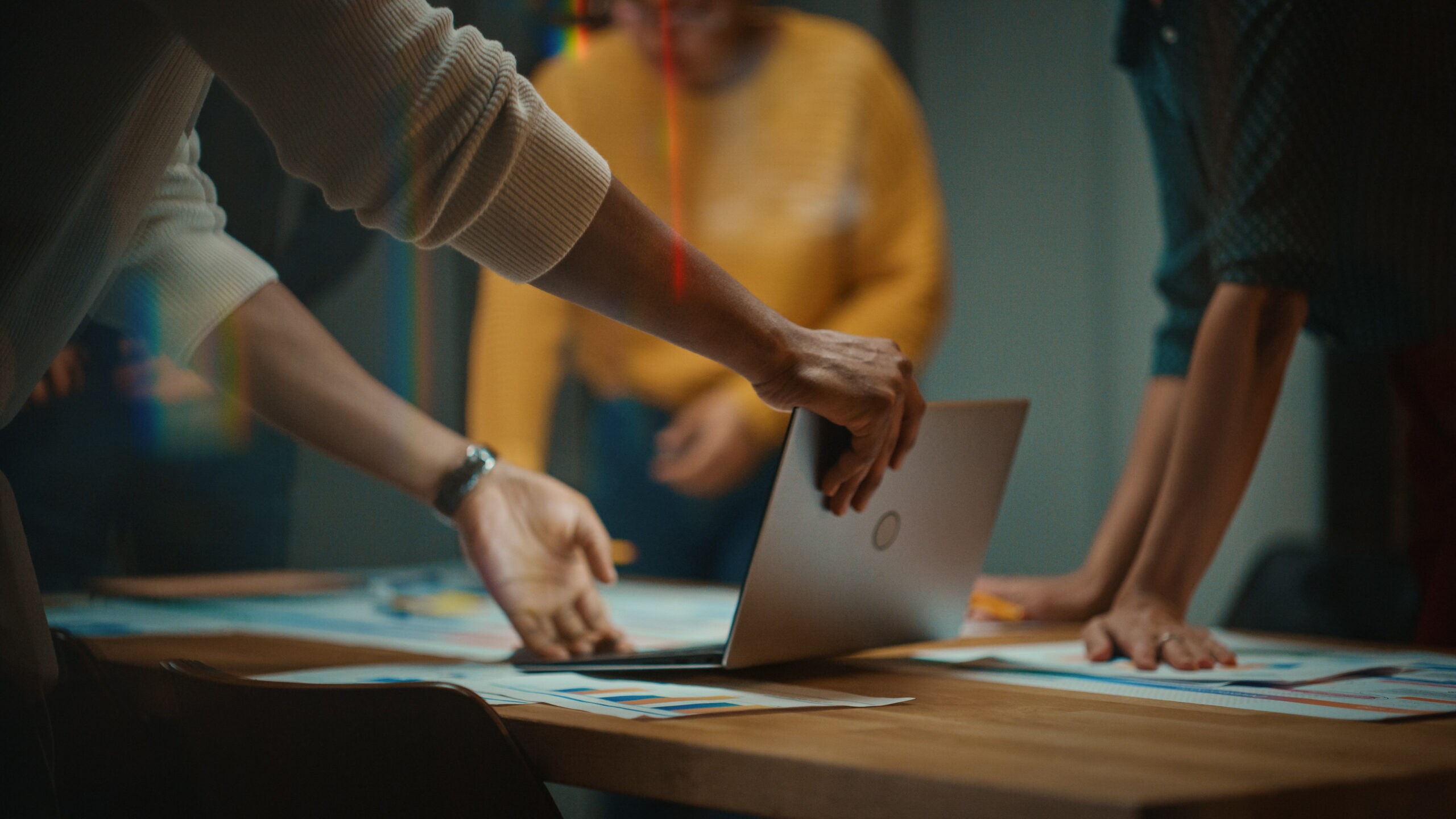 Marketing strategists collaborating around a table, focused on a computer screen for ad planning and strategy development.