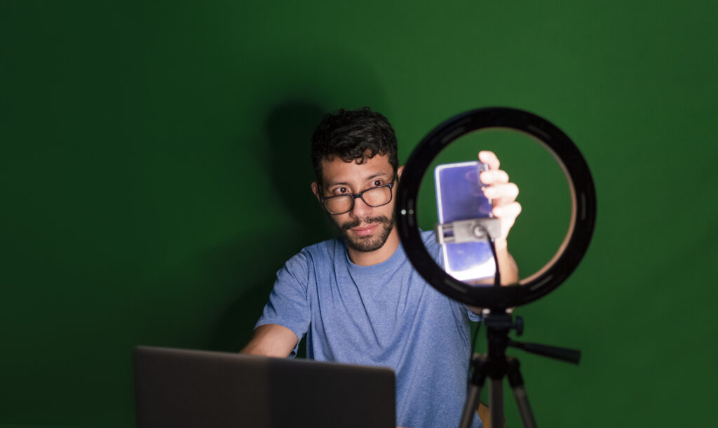 Guy on a video call working Video Production from home. Online classes concept. Man giving online classes with phone. Guy with laptop making video blog on phone. Isolated person giving online classes on Professional Videos